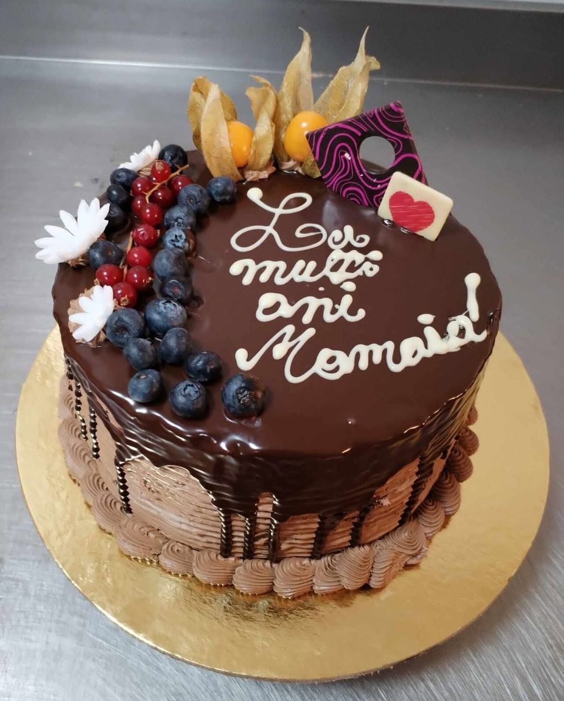 Tort cu glazură de ciocolată, afine, coacăze roșii și mesaj scris cu ciocolată albă